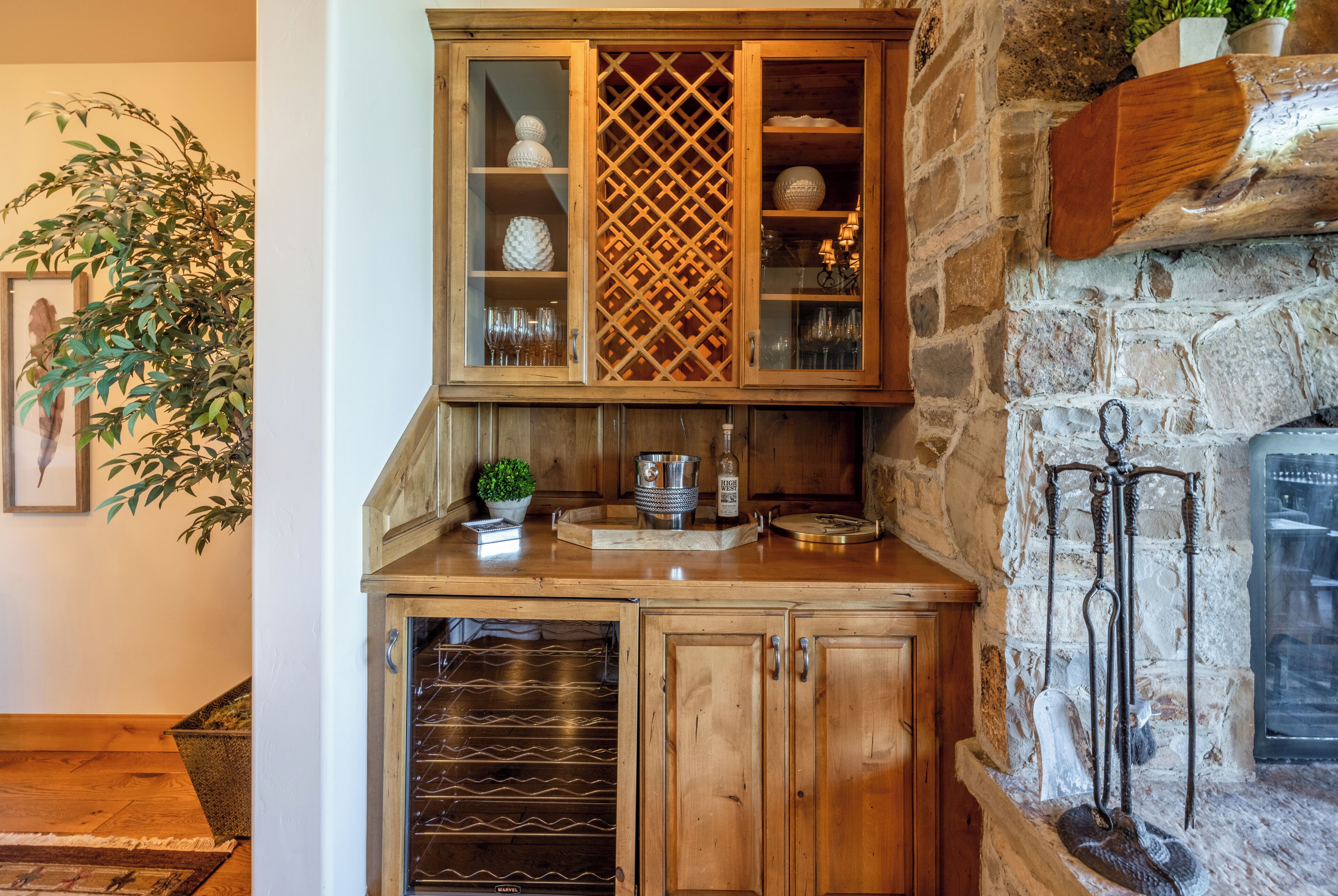 A wooden cabinet with glass doors, a stone wall, and a fireplace.