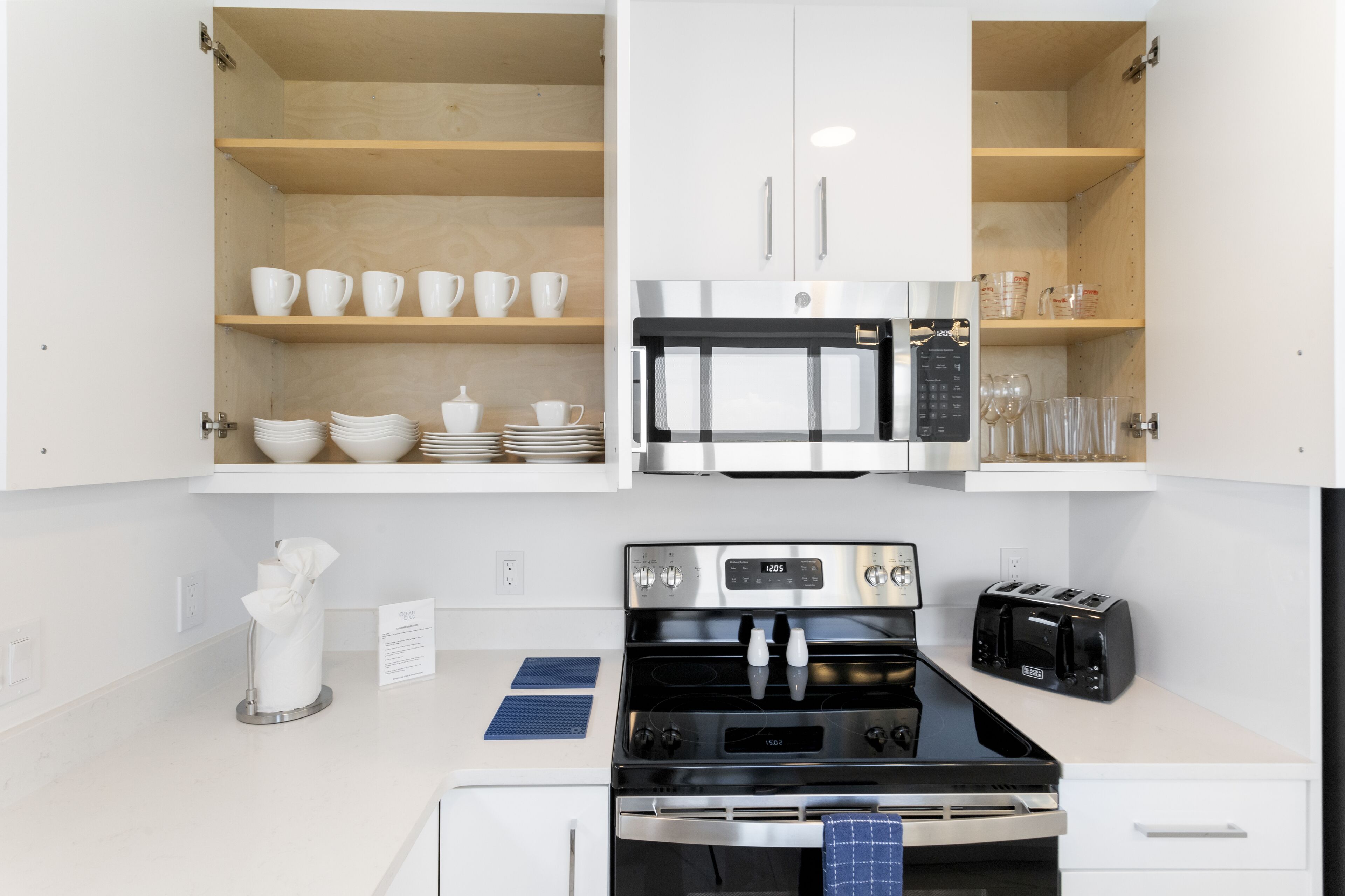 A modern kitchen with white cabinetry, a stainless steel stove, a microwave, and a toaster.