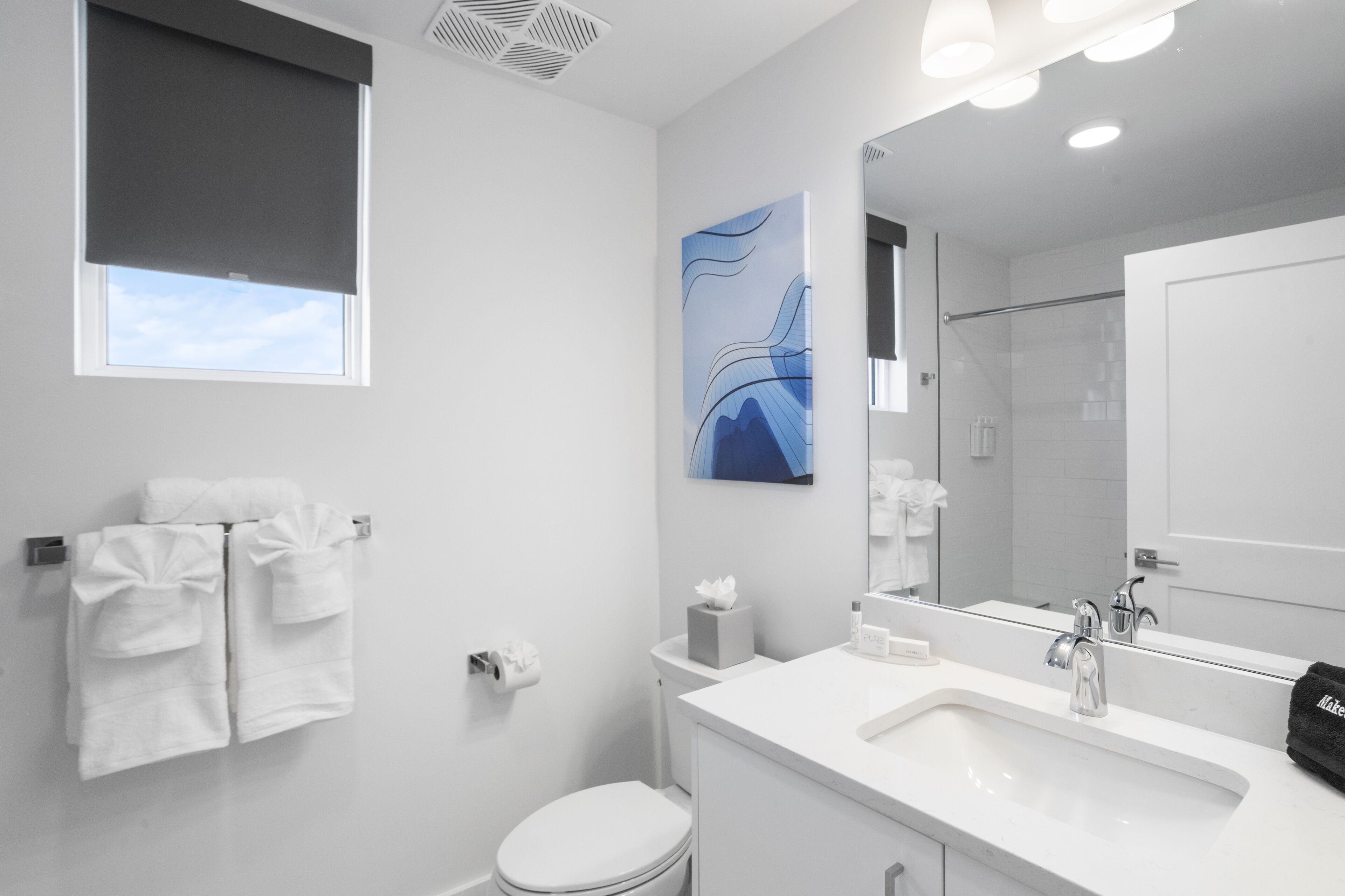 A modern bathroom with a white sink, mirror, and towel rack.