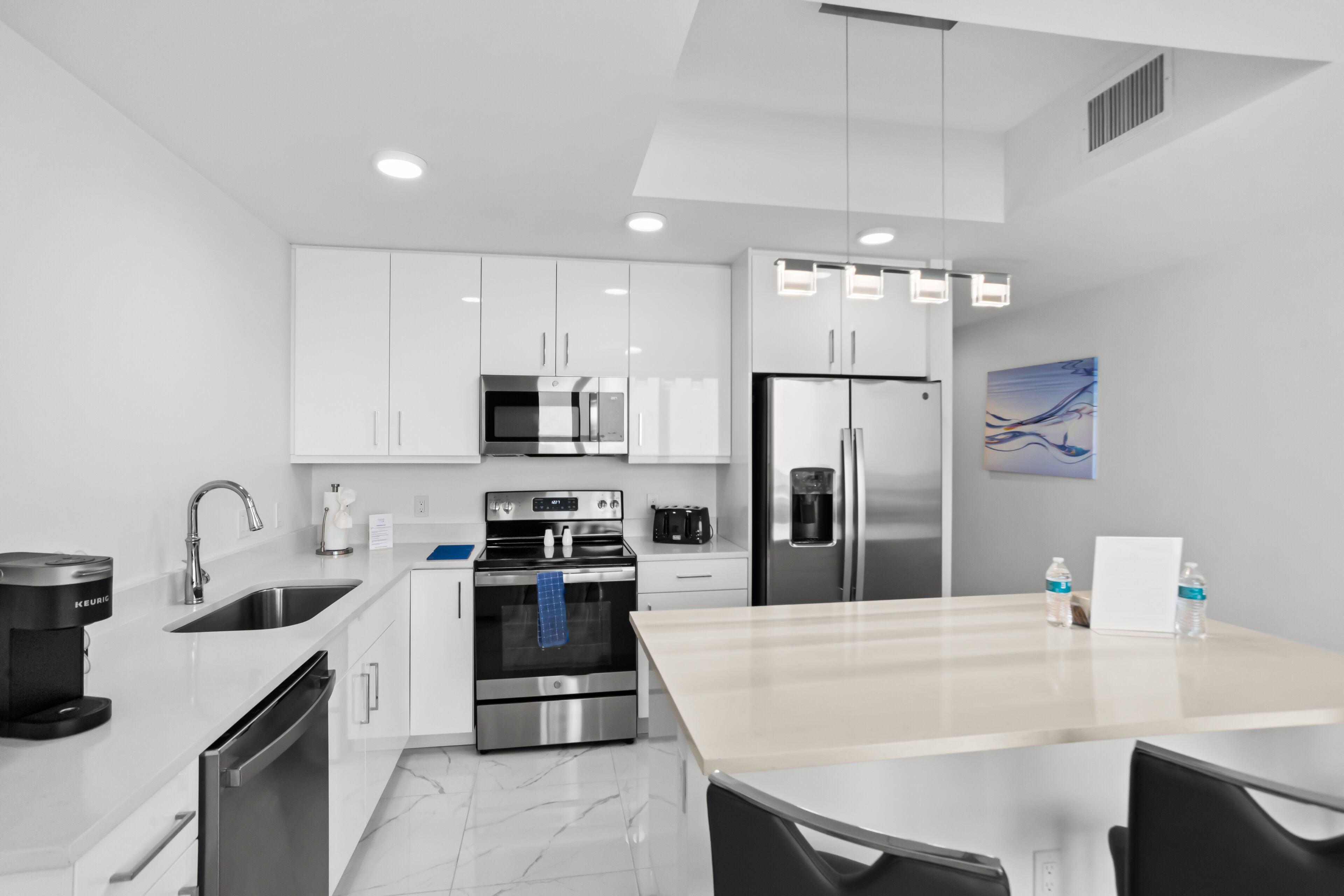 Una cocina moderna con armarios blancos, electrodomésticos de acero inoxidable y una isla central.