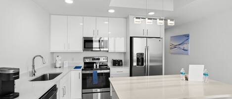 A modern kitchen with white cabinetry, stainless steel appliances, and a central island.
