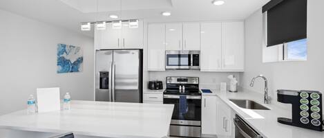 Una cocina moderna con armarios blancos, electrodomésticos de acero inoxidable y una isla grande con asientos.