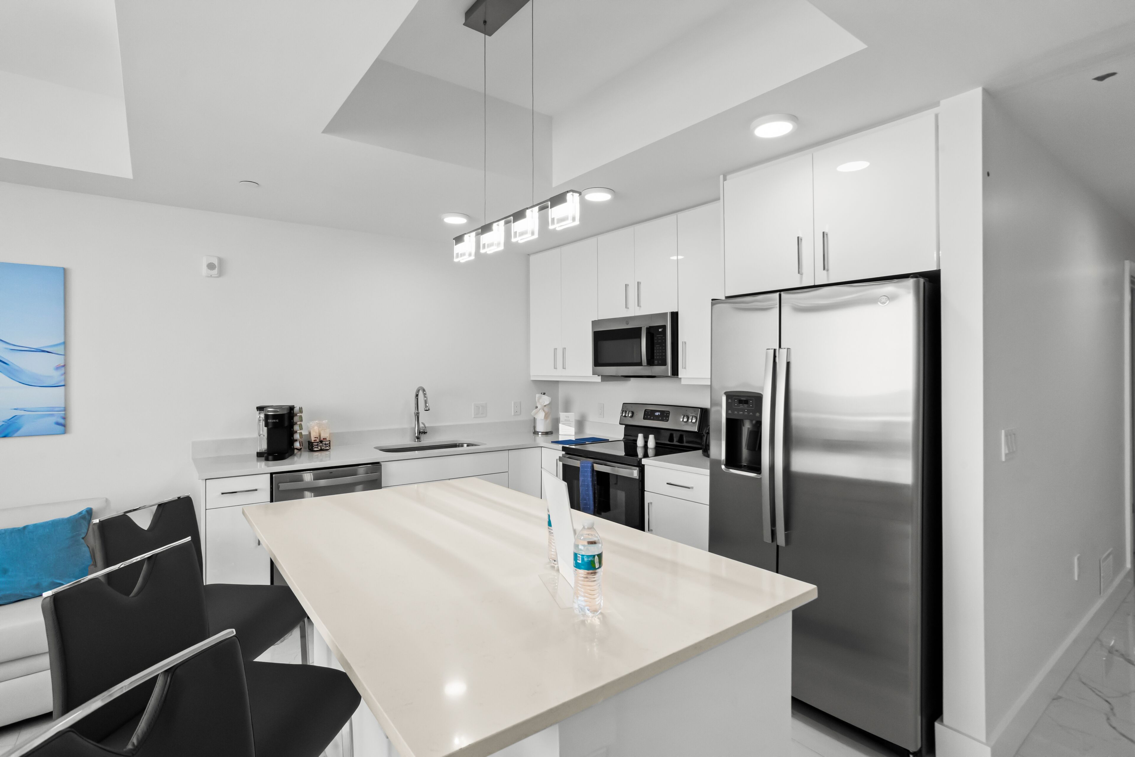 Une cuisine moderne avec des meubles blancs, des appareils en acier inoxydable et un îlot central.