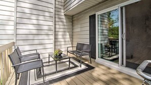 A covered patio with a table and chairs, a small plant, and a sliding glass door leading to an outdoor area.