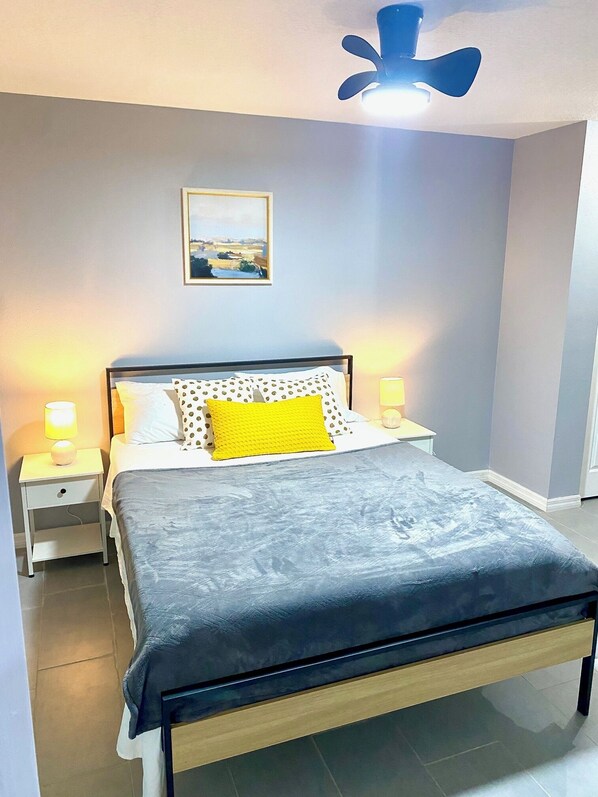 A neatly arranged bedroom with a bed, two bedside tables, a ceiling fan, and a framed picture on the wall. - Cozy 3BR Home in Ocala - For Work Teams & Families (Ocala)
