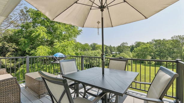 Eine Terrasse mit Tisch, Stühlen, einem Sonnenschirm und einem Grill.