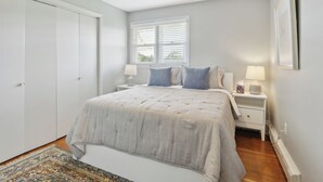 Ein Schlafzimmer mit Bett, Nachttischen, einem Fenster und einem Kleiderschrank.
