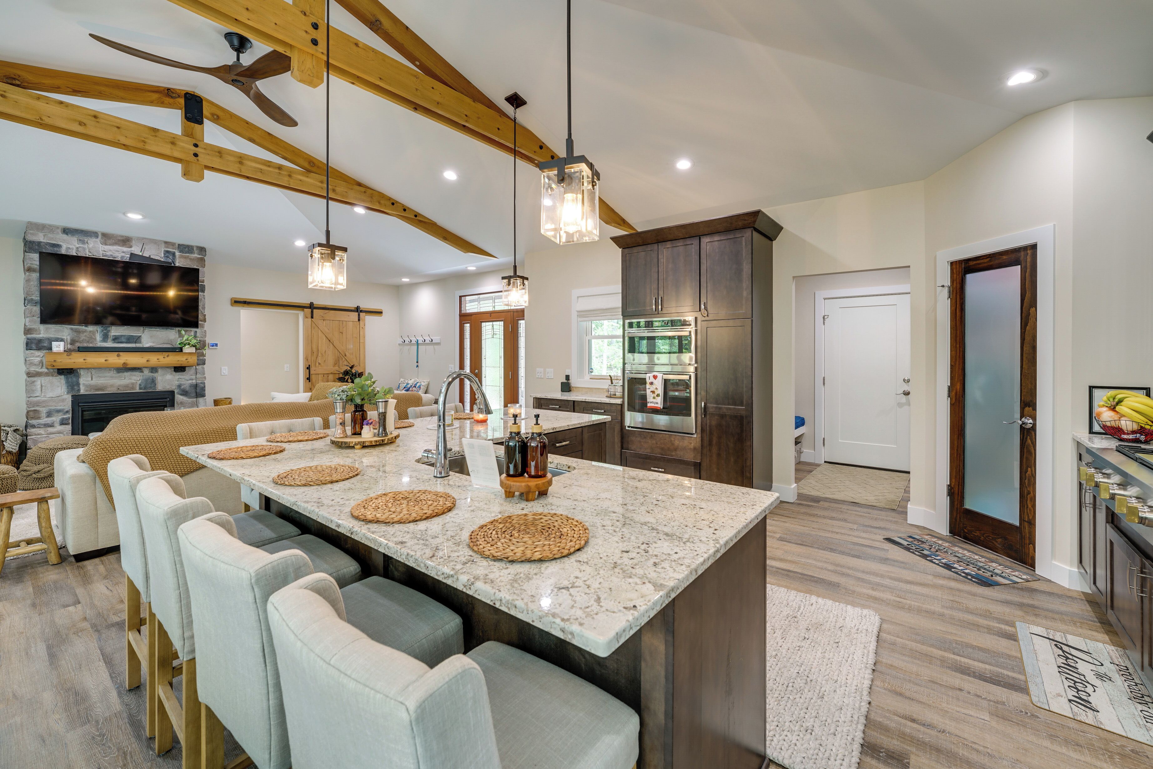 A spacious kitchen with a large island, wooden beams, and modern appliances.