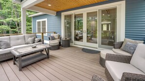Une terrasse extérieure couverte, aménagée avec un canapé, des fauteuils et une table.