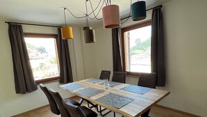 Een eethoek met een houten tafel, zes stoelen en hanglampen.