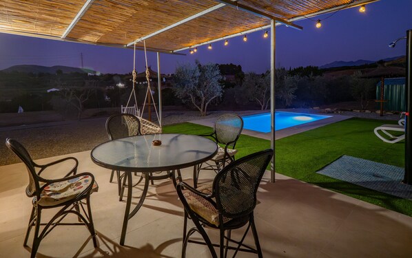 Une terrasse extérieure avec une piscine, des chaises et une table.