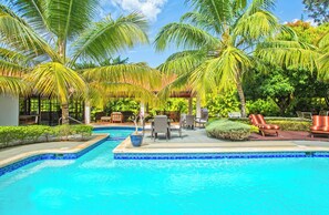 Un espace piscine aménagé avec des chaises longues, une table et une pergola.