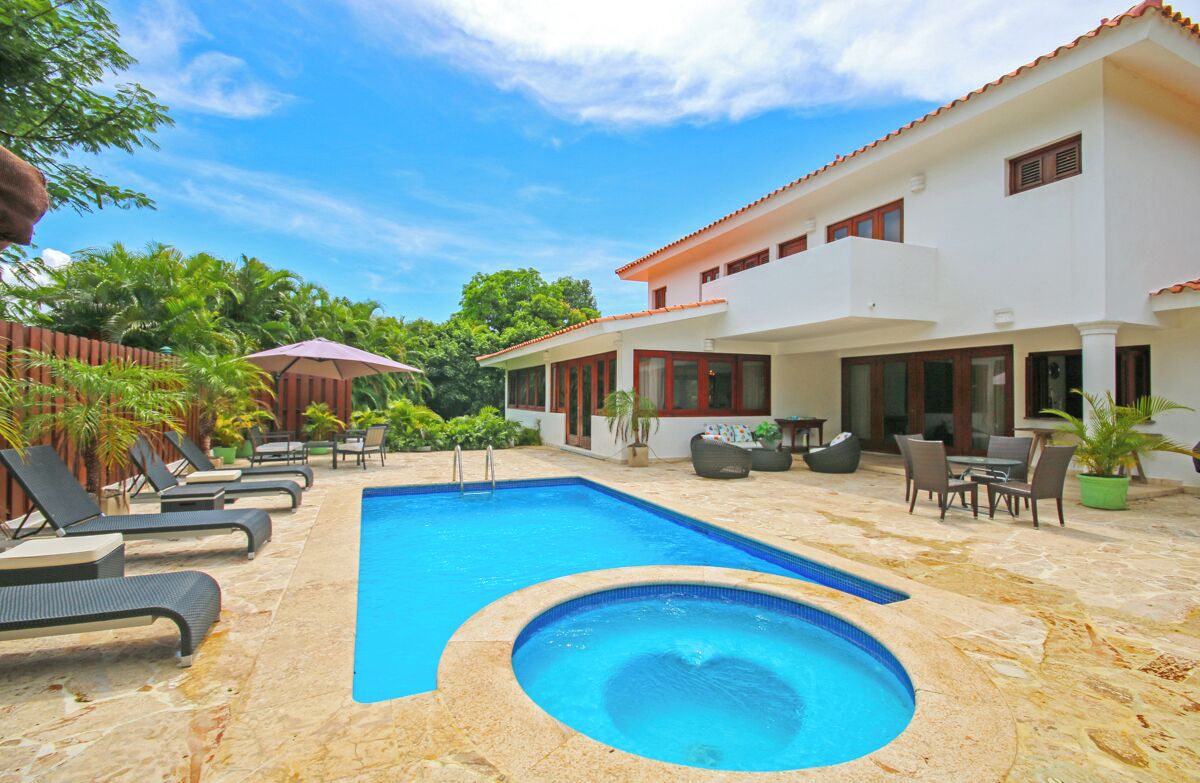 A swimming pool with lounge chairs, a hot tub, and outdoor furniture.