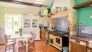 Eine Küche mit weißem Tisch, Stühlen und einem Essbereich.  Ein Herd, ein Backofen und eine Spülmaschine sind vorhanden.