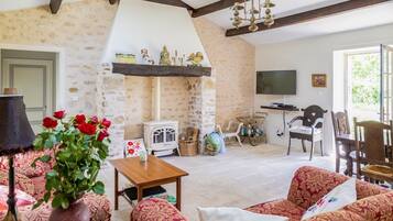 Un salon chaleureux avec une cheminée en pierre, un téléviseur et des fauteuils confortables.