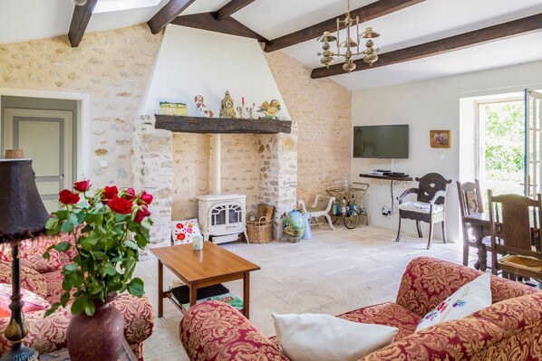 A cozy living room with a stone fireplace, a television, and comfortable seating.