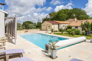 Une piscine avec des chaises longues et un espace aménagé en jardin.