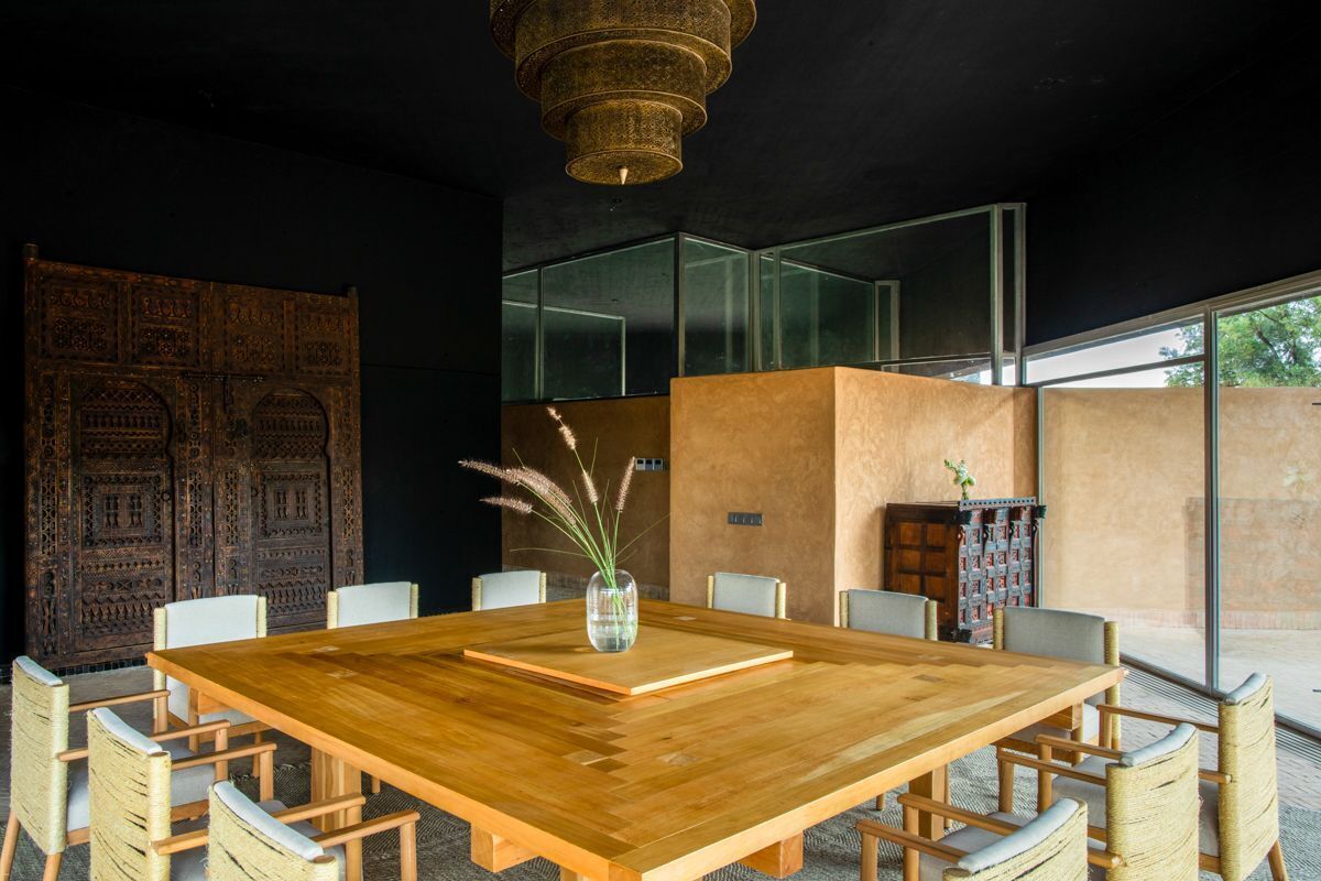 A modern dining area with a large wooden table, white chairs, and a decorative vase.