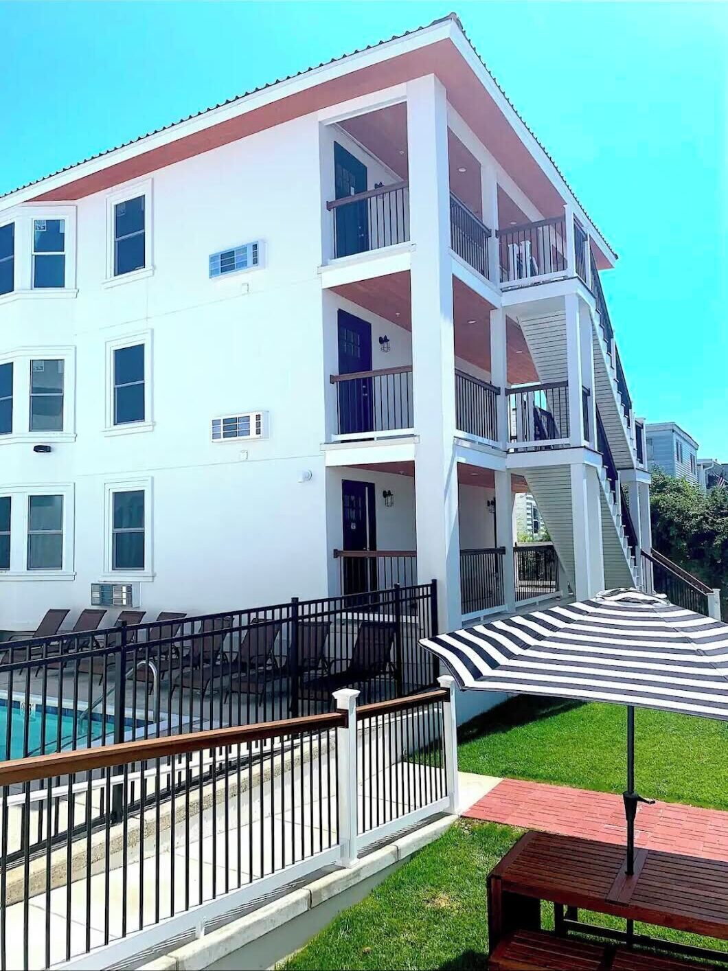 Un edificio de varios pisos con balcones, piscina y una zona de estar techada.