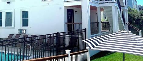 Un edificio de varios pisos con balcones, piscina y una zona de estar techada.