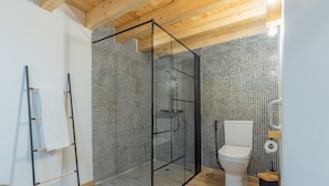 A modern bathroom with a shower enclosure, toilet, and a towel rack. - Casa São José (Carvalhal)