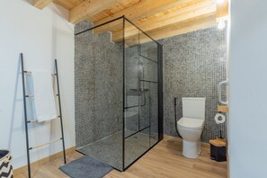 Een moderne badkamer met douchecabine, toilet en handdoekhouder.