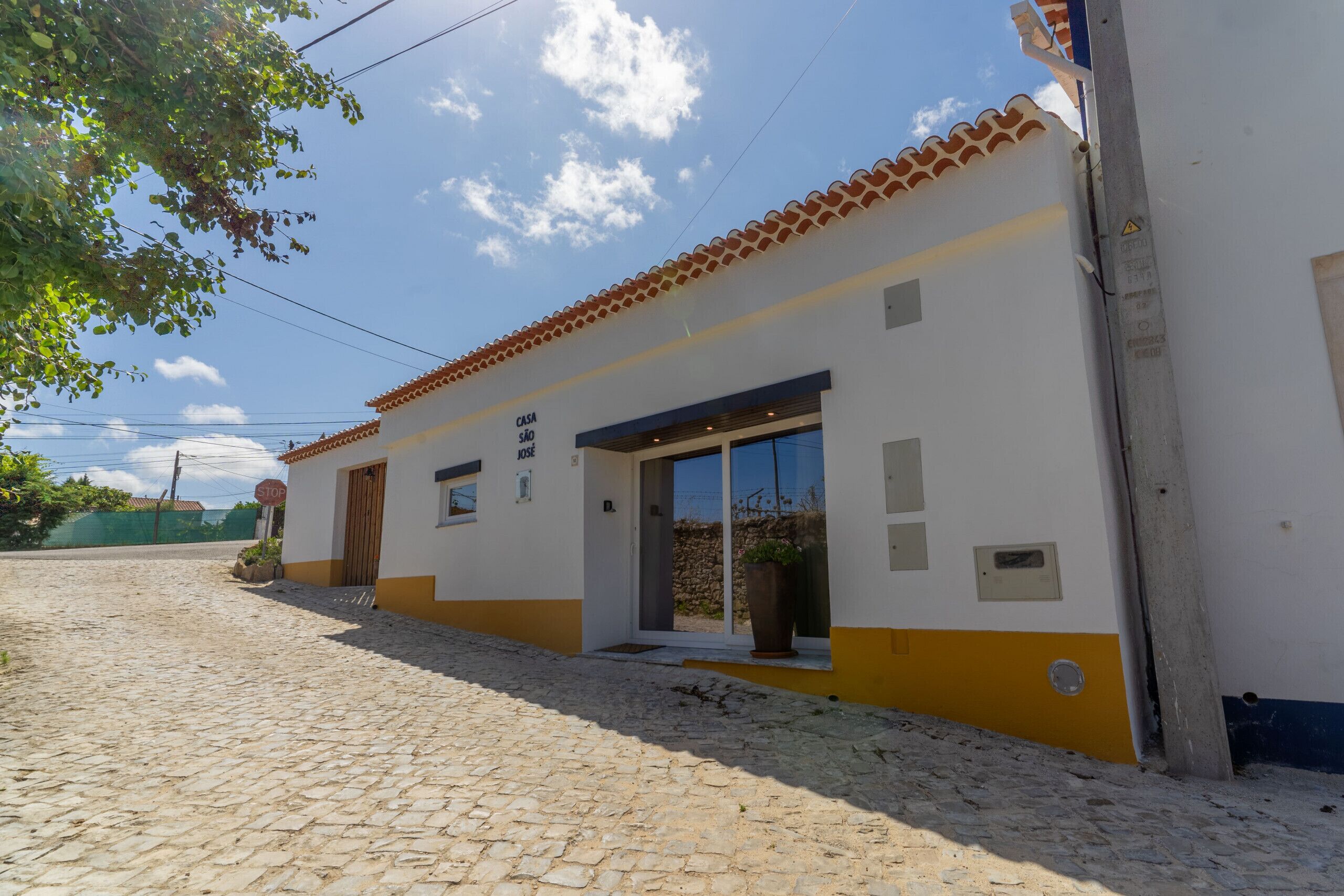 A two-story building with a tiled roof, a stone-paved entrance, and a large window.