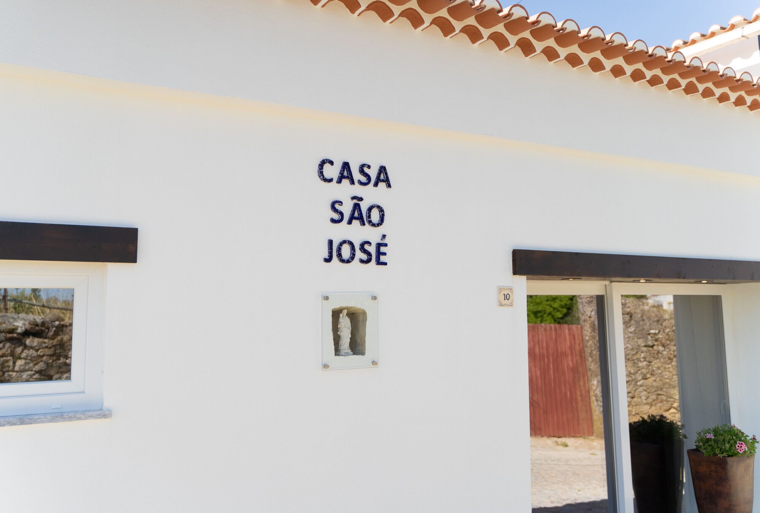 Ein Gebäude mit einem Schild, auf dem 'CASA SÃO JOSE' steht, und einem kleinen Fenster mit einer Statue.