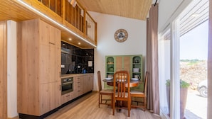 A modern kitchen with wooden cabinets, a built-in oven, and a dining area with a table and chairs. - Casa São José (Carvalhal)