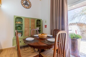 A dining area with a wooden table, chairs, and a green cabinet with shelves.