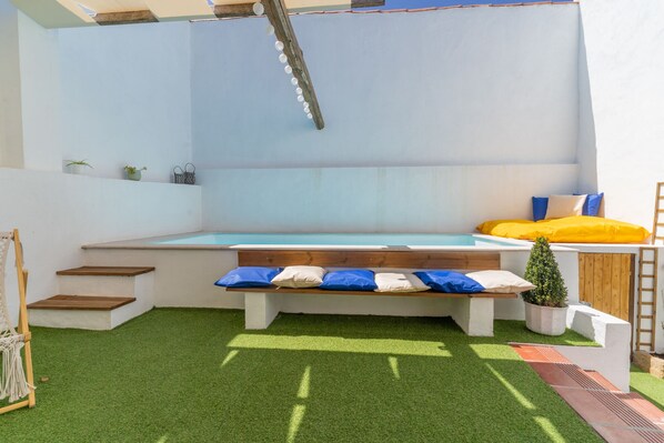 A pool area with a wooden bench, steps, and a small potted plant.