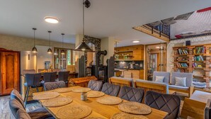 Un vaste espace dédié à la salle à manger, avec une longue table en bois, des chaises rembourrées et des sets de table en fibres tressées.