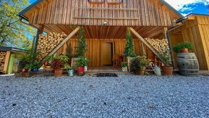 Une grange en bois dotée d’un porche, entourée de gravier et agrémentée de plantes en pot.