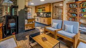 Un salon chaleureux avec une cheminée, des meubles en bois et une cuisine en arrière-plan.