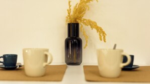 A table with a vase of dried plants, two cups, and a saucer. - Via Duomo 196 - Studio Apartment, Sleeps 2 (Naples)