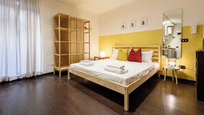 A bedroom with a wooden bed, a wardrobe, a bedside table with a lamp, and a mirror on the wall. - Via Duomo 196 - Studio Apartment, Sleeps 2 (Naples)