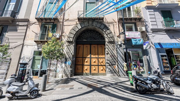 A building with a large wooden door, multiple balconies, and a scooter parked in front. - Via Duomo 196 - Studio Apartment, Sleeps 2 (Naples)