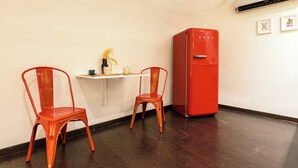 A room with two red chairs, a small white table, and a red refrigerator. - Via Duomo 196 - Studio Apartment, Sleeps 2 (Naples)