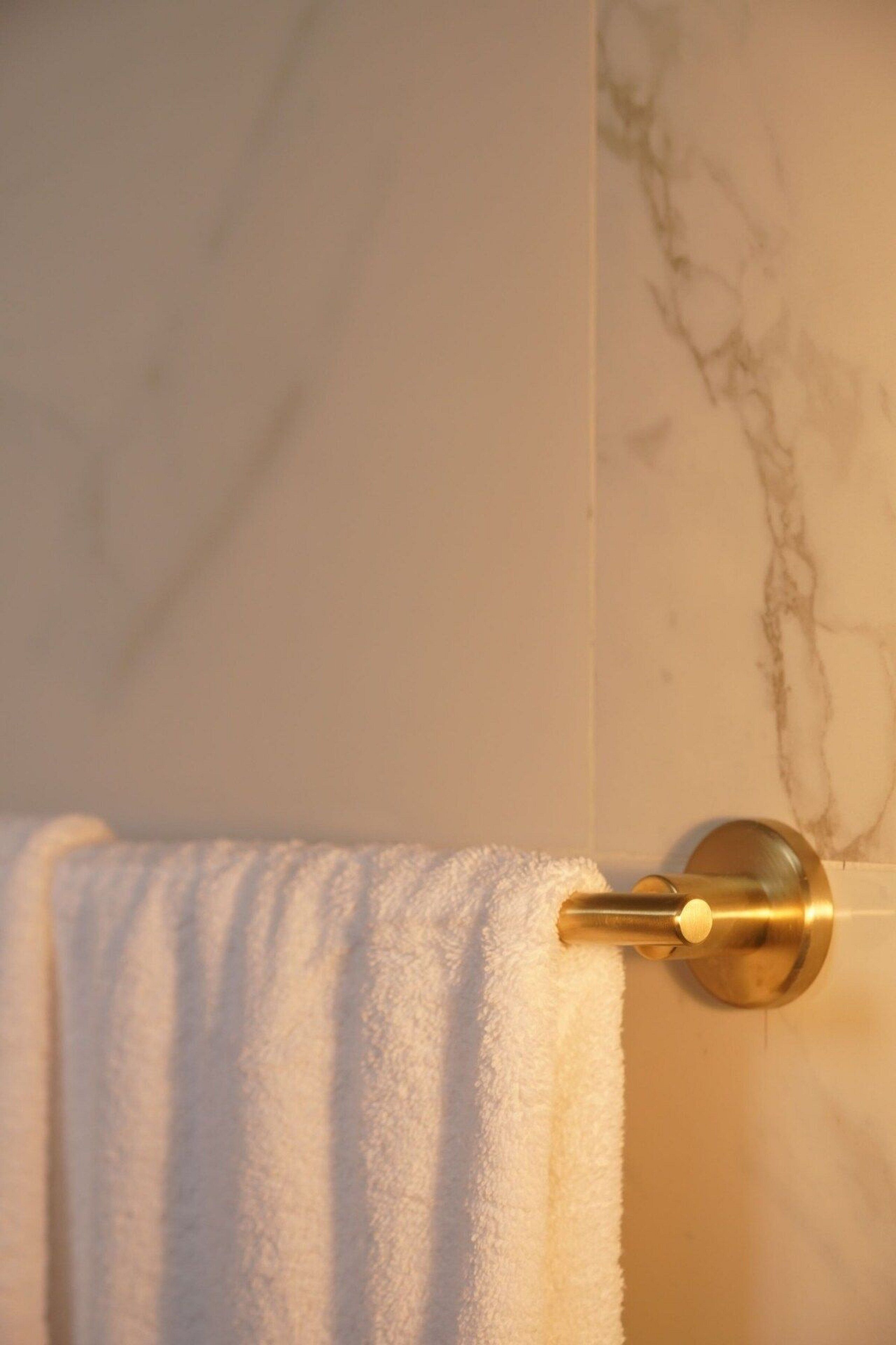 A bathroom with a marble wall and a towel rack with a white towel.