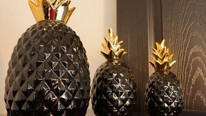 Three black, textured vases with golden pineapple tops on a dark countertop. - Cabaña El Encino III en Real del Monte (Mineral del Monte)