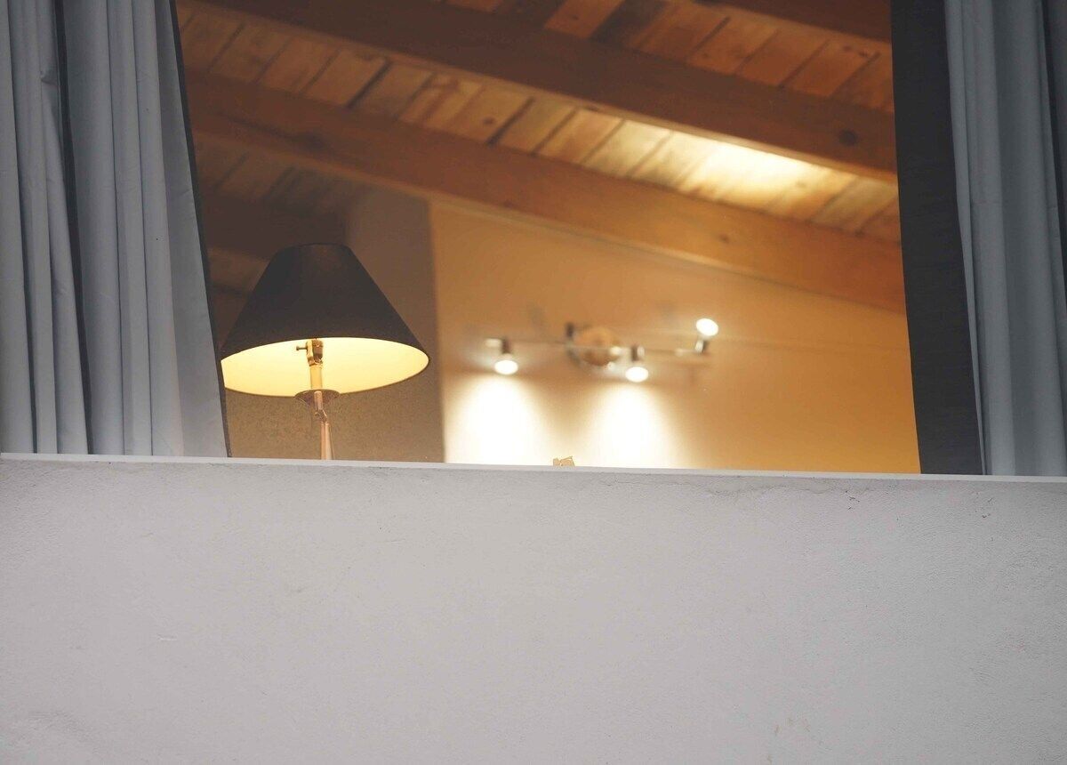 A room with a wooden ceiling and a lamp in the corner.