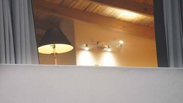 A room with a wooden ceiling and a lamp in the corner.