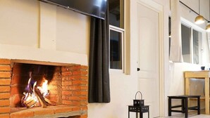 A living room with a fireplace, a flat-screen TV mounted above it, a wooden table, and a fluffy rug. - Cabaña El Encino III en Real del Monte (Mineral del Monte)