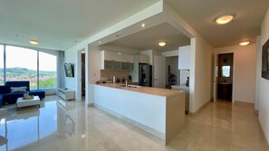 A modern kitchen with a central island, large windows, and a view of the outdoors.