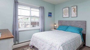 A bedroom with a bed, a nightstand, a window with curtains, and two wall-mounted pictures. - Lovely- 3 Bedroom apt in Vaca Beach home (Hampton)