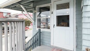 A front porch with a white door, a small window, and a metal railing. - Lovely- 3 Bedroom apt in Vaca Beach home (Hampton)