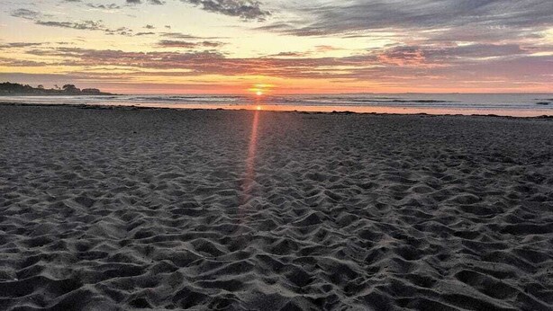 A beach at sunset with the sun setting over the horizon. - Lovely- 3 Bedroom apt in Vaca Beach home (Hampton)