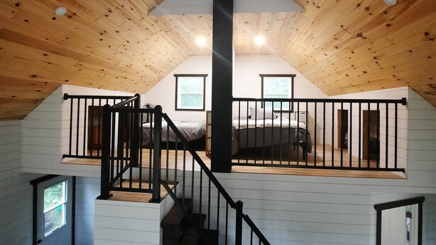 Ein Loft-Zimmer mit Holzbalkendecke, einer Treppe, einem Bett und einer Küchenzeile.