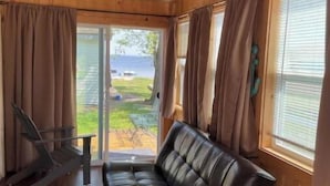 Eine Holzhütte mit Ledersofa, Schaukelstuhl und kleinem Tisch.