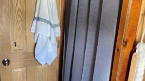 Eine Holztür mit einem darüber hängenden Handtuch, ein grauer Vorhang und eine Wand aus Holzverkleidung.